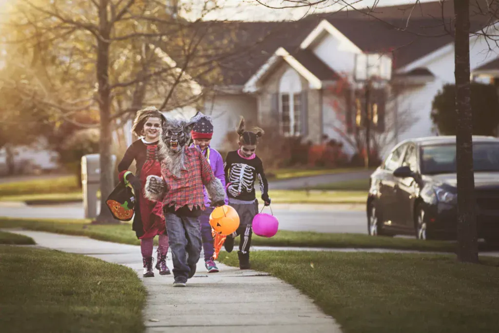 Children going trick-or-treating in costumes for Halloween.
