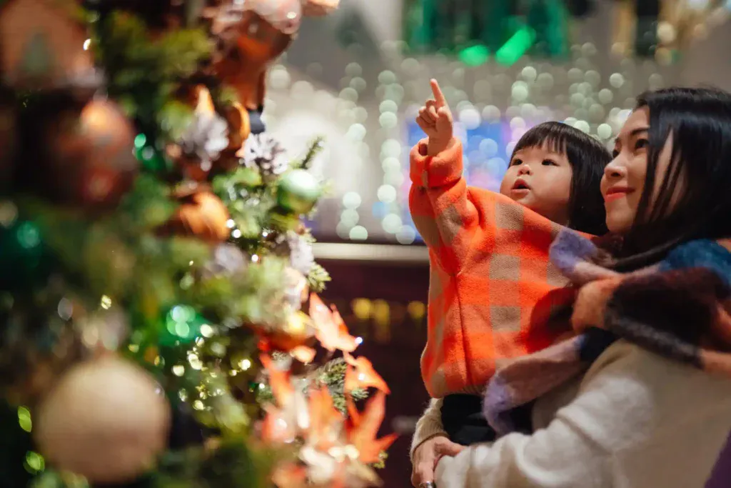 A mother and her kid admire their Christmas tree.